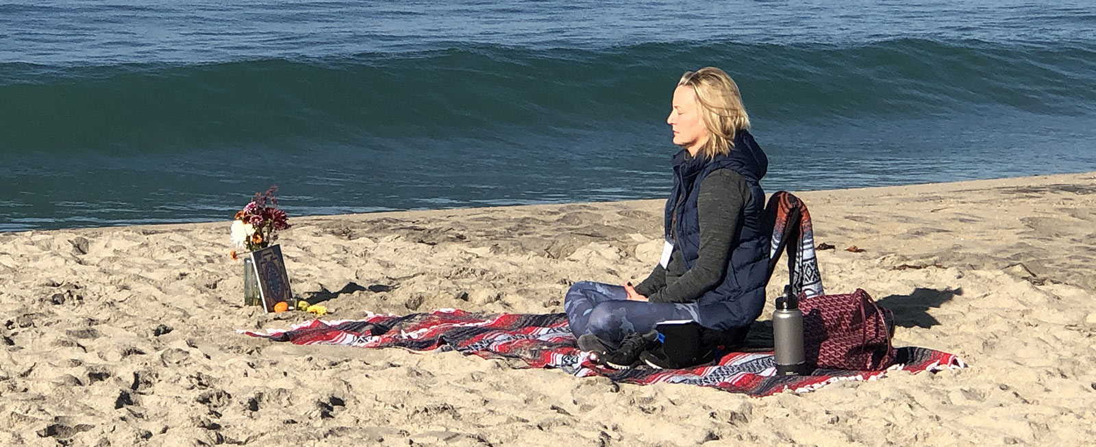 Elizabeth meditates on beach with ocean in background