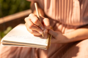 Close up of woman writing in her journal in the morning sunshine