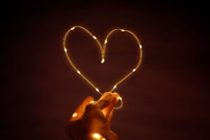 Hand holding heart with LED lights and red backround